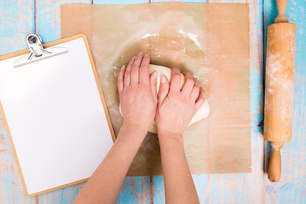 Hands preparing dough on wooden board
